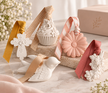 Load image into Gallery viewer, A styled product display of pastel decorative items on a marble surface, including a white ceramic angel figurine, a white cupcake ornament with a gingham ribbon, a pink flower-shaped ornament with a striped ribbon, a white floral ornament with a mustard ribbon, and a pink ribbon bow.