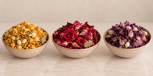 Load image into Gallery viewer, Ceramic bowls filled with dried botanicals on a light marble: a bowl of golden chamomile flowers, a bowl of deep red dried roses, and a bowl of purple dried lavender buds. Wedding favours rovistella
