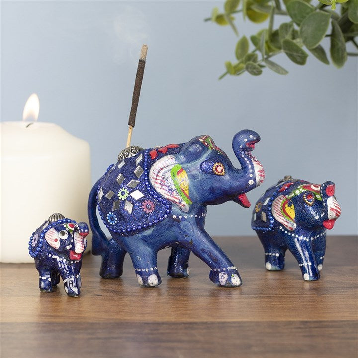  'This elegant set of resin incense holders includes 5 different sizes of ornate blue elephants. Beads, glitter and tiny mirrors beautifully accent colourful, hand-painted details. Each elephant holds one incense stick. Largest elephant measures 9 cm long and the smallest measures 4 cm long. No incense sticks included. Used as a elegant and oriental style decorative item Gift box included'. 