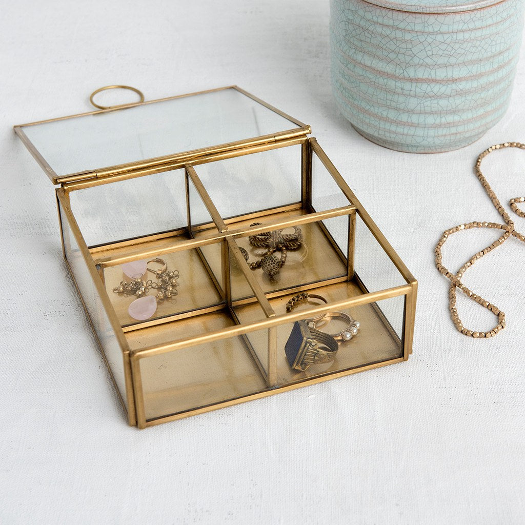From the Jaipur glassware collection, this four-compartment brass jewellery box is a classic way to store earrings, bracelets and more. Useful home decor item and gift idea!  Brass 4 compartment jewellery box, Each compartment measures: 7 x 7 x 4.5cm; Padding on each corner to avoid damage to surfaces; Material Glass, Brass