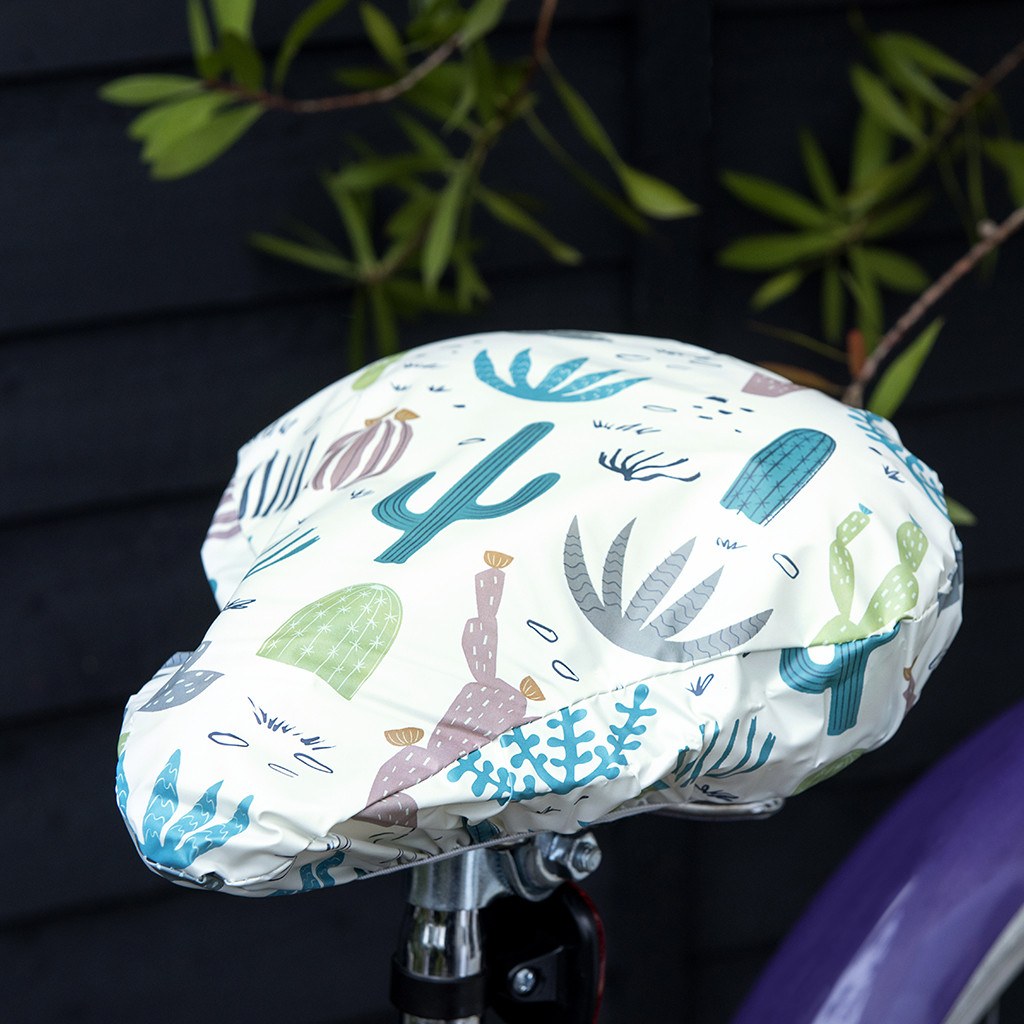 Say goodbye to plastic bags on bike seats in the rain! An original funny design with hand drawn succulent and cactus illustrations, this elasticated Desert in Bloom waterproof saddle cover is both pretty and functional. Size of cover: 23cm (width) x 24.5cm (length) One size fits all. Material: Card, Plastic, Elastic Dimensions: Length: 35 cm Height: 0.5 cm Width: 26.5 cm. Cyclists riders lovers gift idea.